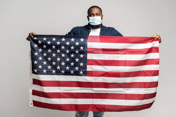 Serious African-American guy holding american flag - Foto, imagen