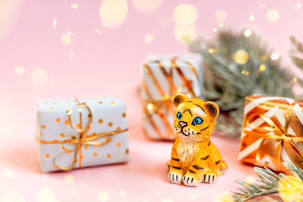 Tigre símbolo del nuevo año chino 2022. Figura de tigre con ramas de abeto y cajas de regalo doradas sobre fondo pastel rosa. Copiar espacio. - Foto, Imagen