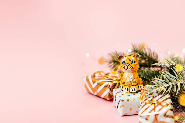 Tijgersymbool van het Chinese nieuwjaar 2022. Figuur van tijger met takken sparren boom en gouden geschenkdozen op roze pastel achtergrond. Kopieerruimte. - Foto, afbeelding