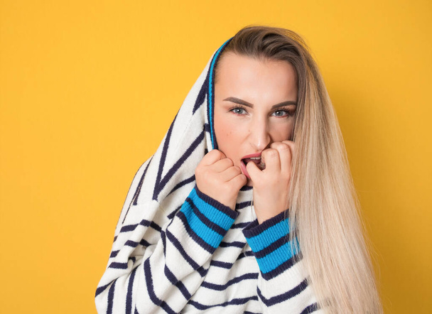 Panicked young woman biting fingernail, being terrible accident, isolated on yellow background. Frightened girl. Studio shot - Photo, Image