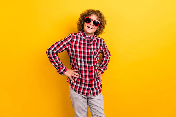 Photo of funky ginger hairstyle small boy wear eyewear red checkered shirt isolated on yellow color background - Foto, imagen