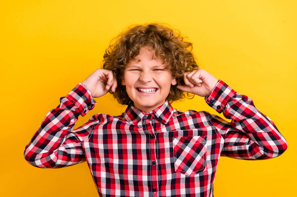 Photo of yell orange wavy hairdo teen boy close ears wear red checkered shirt isolated on yellow color background - Valokuva, kuva