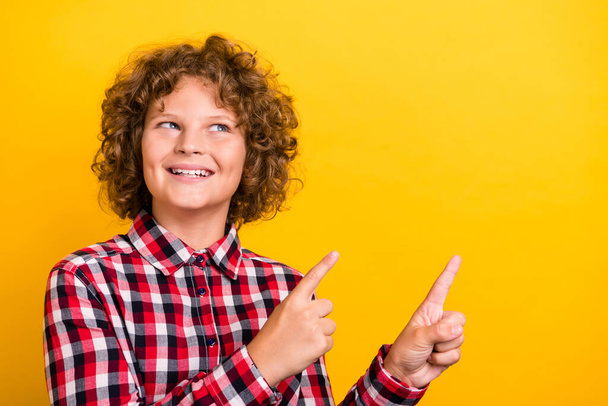 Photo of cute ginger hairdo teen boy index look empty space wear red checkered shirt isolated on yellow color background - 写真・画像