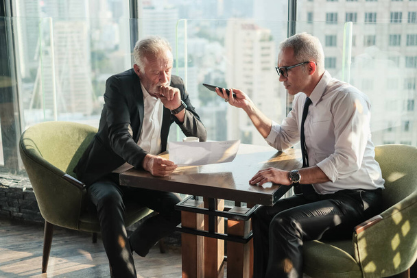 Twee senior zakenman koppel vergadering in co werkruimte op wolkenkrabber lounge of kantoor - Foto, afbeelding