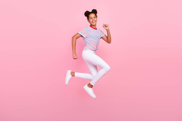 Full body photo of childhood african american brunette haired stylish trendy girl wear casual clothes jump run isolated on pink color background - 写真・画像