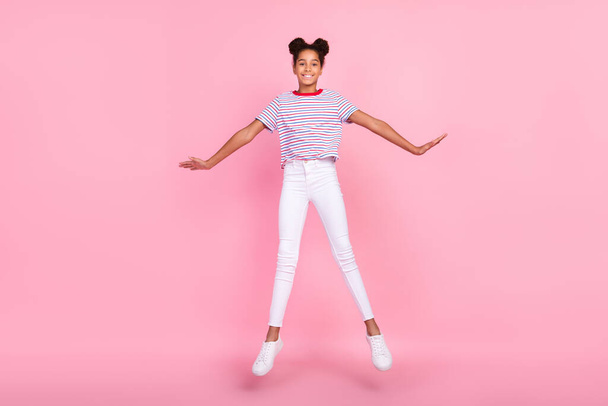 Full body photo of brown bun haired stylish trendy african american girl wear casual outfit jump isolated on pink color background - Foto, Bild