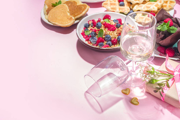 Valentine day brunch menu background with various breakfast and lunch dishes, waffle, croissant, muffins, donuts, berries, fries scrambled eggs, pancakes, pink background copy space - Photo, Image