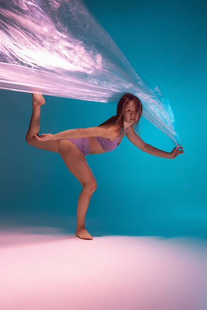 One young flexible contemp dancer dancing with fabric isolated on gradient blue white background in neon light - Fotografie, Obrázek