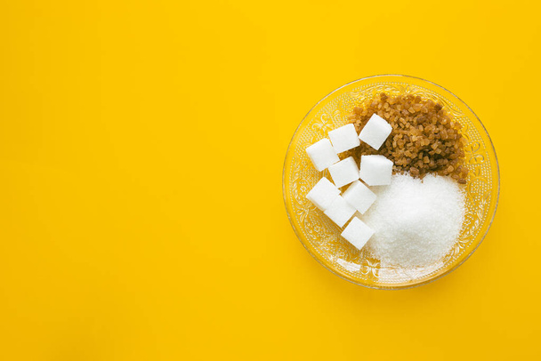 Различные виды сахара для подслащивания на желтом стекле, место для надписи, концепция здоровья  - Фото, изображение