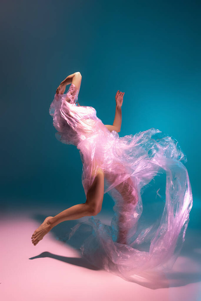 Solo performance. Beautiful flexible contemp dancer dancing with fabric isolated on gradient blue white background in neon light - Foto, immagini