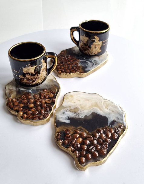 Черные блестящие подставки из эпоксидной смолы и стекла, черная керамическая чашка для кофе  - Фото, изображение