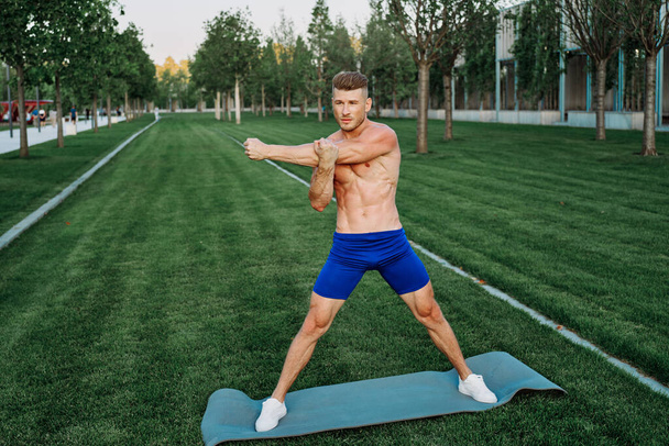 athletic man in blue shorts working out in the park - Foto, Imagem