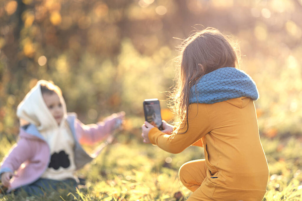 Κορίτσι πυροβολεί ένα blog στο τηλέφωνο στη φύση το φθινόπωρο, θέα από πίσω - Φωτογραφία, εικόνα