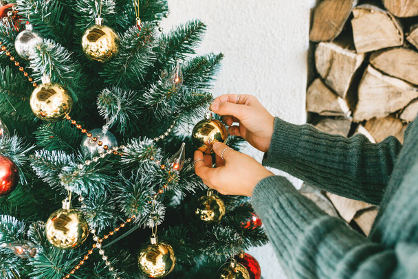 A woman decorates a Christmas tree at home.  - Fotó, kép