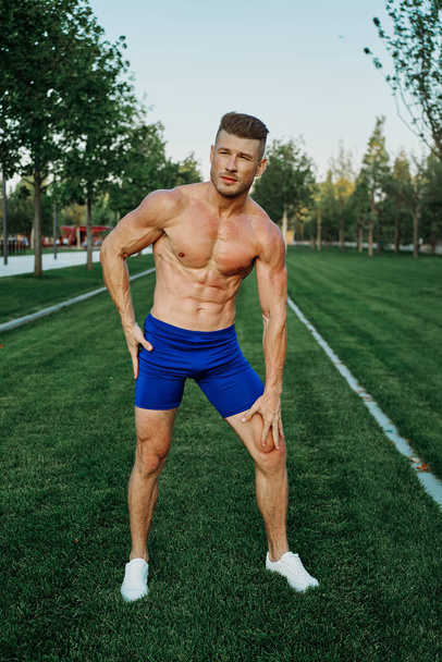 sporty man with muscular body pumping in park workout - Фото, зображення