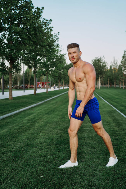 athletic man with a pumped-up torso exercise in the park fitness - Фото, зображення