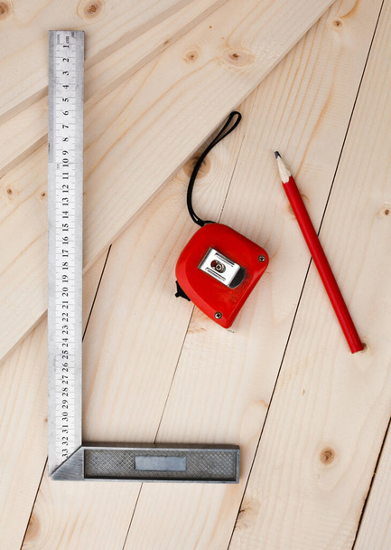 A measuring tape, a square and a pencil. Tools for measuring. Joiner's (carpenter's) workshop. Close-up. - Foto, afbeelding