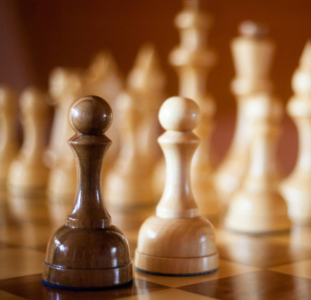Wooden chess pieces on the chessboard. Black and white pawns in the foreground.  - Foto, Imagem