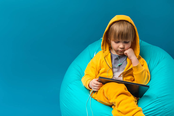 Дитяча концепція дозвілля, цифрове технологічне дитинство. Дитина дивиться ноутбук, комп'ютер, планшет. Слухати музику з навушниками
. - Фото, зображення