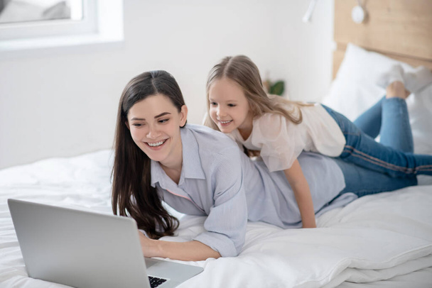 Kid and her mom watching a video on the laptop - Foto, Imagem