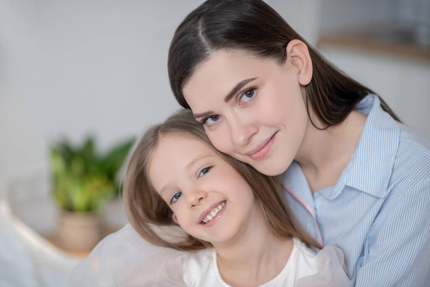 Happy mother and her joyful daughter posing for the camera - Фото, зображення