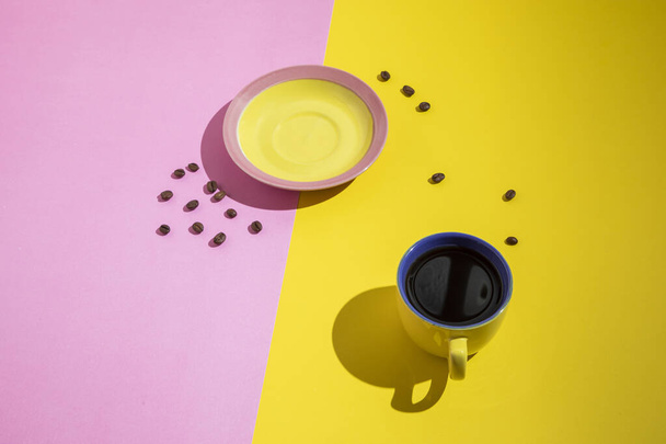 bandeja amarillo-rosa, taza de café y granos de café, sobre un fondo amarillo-rosa. - Foto, Imagen