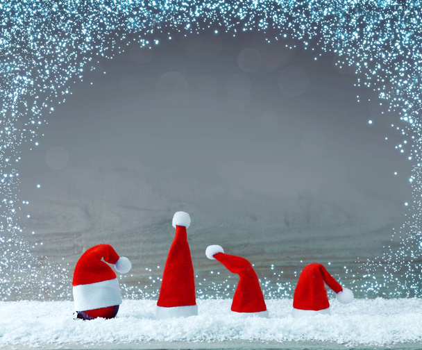 Cuatro sombreros rojos de Santa Claus sobre nieve blanca . - Foto, imagen