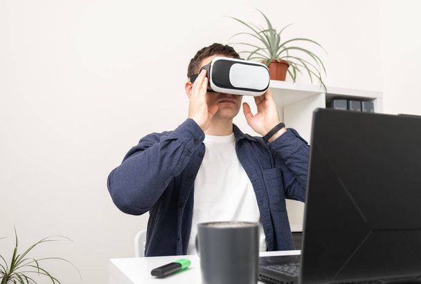 A man works at a laptop in reality glasses. Vr game programmer. - 写真・画像