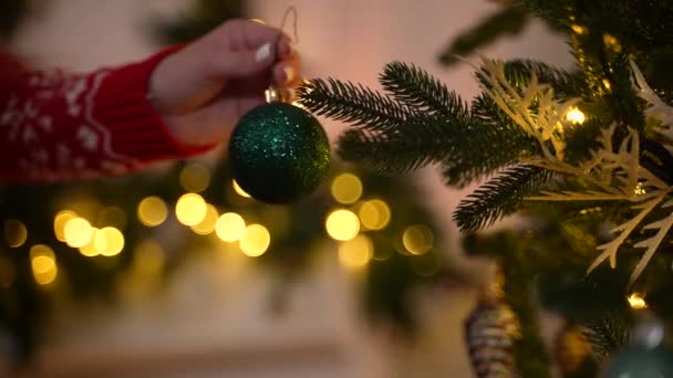 Χέρι του κοριτσιού κρέμεται μπάλα Χριστουγέννων σε έλατο δέντρο - Πλάνα, βίντεο