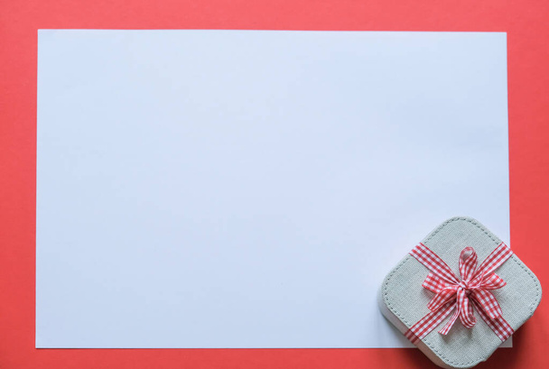 Le cadeau, attaché avec un ruban, repose sur un fond blanc avec un cadre rouge. - Photo, image