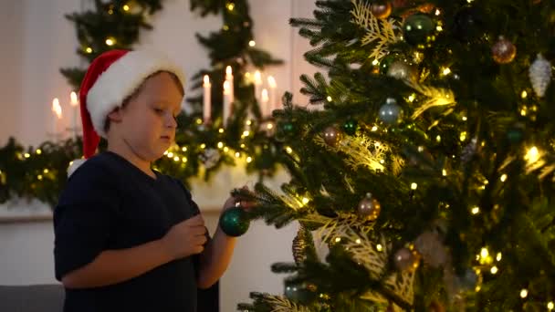 Lindo niño pequeño decorando el árbol de Navidad en casa - Imágenes, Vídeo