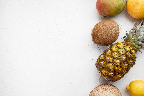 Tropické ovoce, ananas, mango a pomeranče set, na bílém kamenném stole pozadí, horní pohled plochý ležel, s kopírovacím prostorem pro text - Fotografie, Obrázek