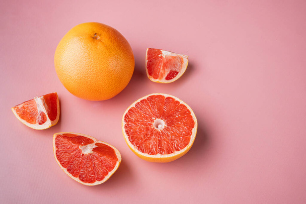 Ripe slice of pink grapefruit citrus fruit set, on pink textured summer background, with copy space for text - Фото, изображение