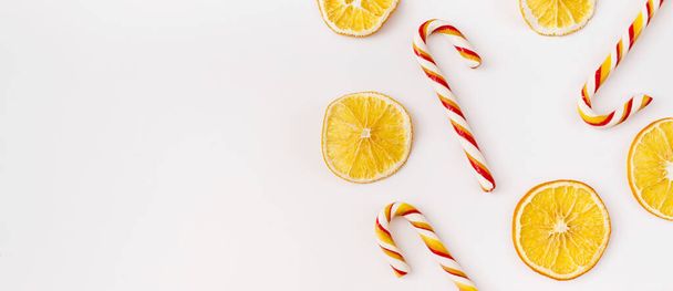 Christmas Banner. winter, new year composition. Slices of dry oranges and candies on white background. Food background. Flat lay, top view, copy space. - Photo, image