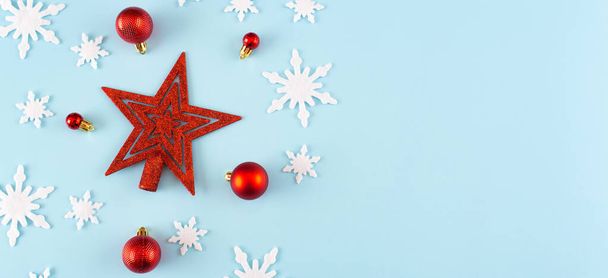 Christmas composition. Banner made of snowflakes, red decorations on blue background. Christmas, winter, new year concept. Minimal style. Flat lay, top view, copy space - Foto, Bild