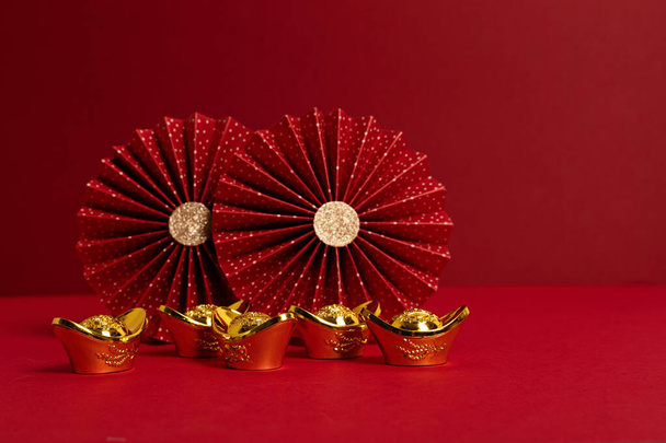 Chinese new year festival decoration over red background. traditional lunar new year gold ingots, paper fans. Copy space - Photo, Image