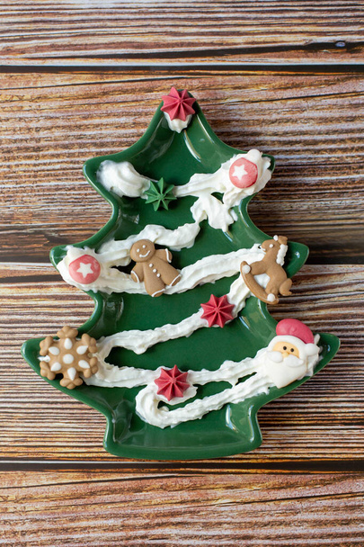 Vánoční stromeček zdobené pečivem a další dekorace jsou na dřevěném pozadí. Svislá fotografie.  - Fotografie, Obrázek