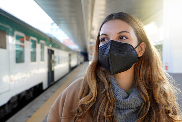 Tren istasyonunda siyah koruyucu maske takan genç bir kadının portresi KN95 FFP2 - Fotoğraf, Görsel