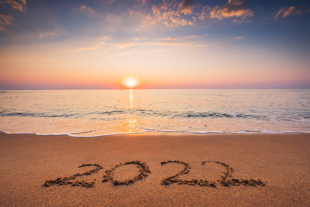 З Новим 2022 роком концепція, випущена на пляжі. Письмовий текст на морському пляжі на сході сонця
. - Фото, зображення