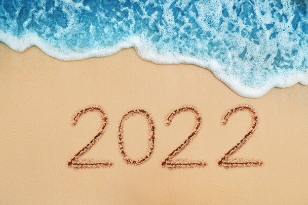 Happy New Year 2022 Konzept, Schriftzug am Sandstrand. Sonnenaufgang im Meer. - Foto, Bild