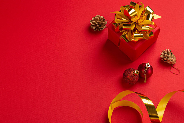 Vánoční červený dárek se zlatým lukem a kulatými dekoracemi horní pohled - Fotografie, Obrázek