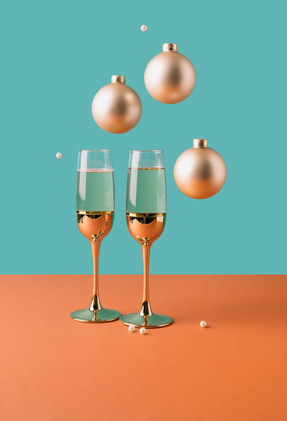Dwa złote kieliszki do szampana z ozdobami uroczystości wiszącymi nad nami. Surrealistyczna koncepcja nowego roku minimalna - Zdjęcie, obraz