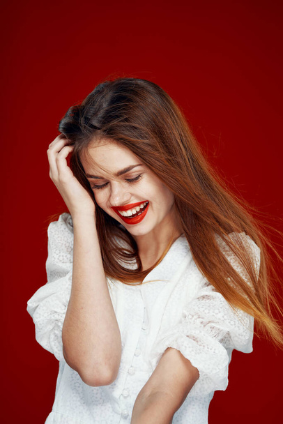 cheerful red-haired woman with red lips white dress red background - Foto, imagen