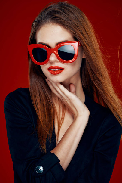 pretty woman wearing sunglasses fashion posing hairstyle red background - Fotó, kép