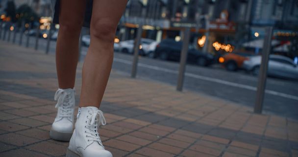 Θηλυκά πόδια με τα πόδια κάτω από το δρόμο το βράδυ της πόλης κοντά σε φανάρια. - Φωτογραφία, εικόνα