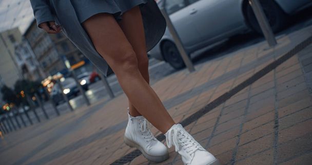 Κορίτσι πόδια με τα πόδια της πόλης κοντά στην εθνική οδό με διερχόμενα αυτοκίνητα το σούρουπο. - Φωτογραφία, εικόνα