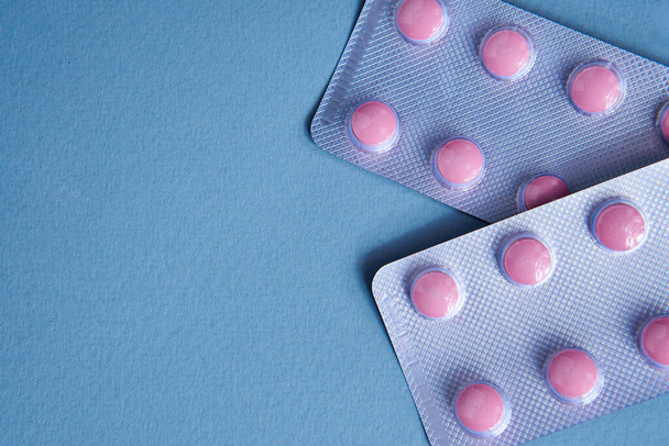 pink pills in packs vitamins pain reliever blue background - Fotó, kép