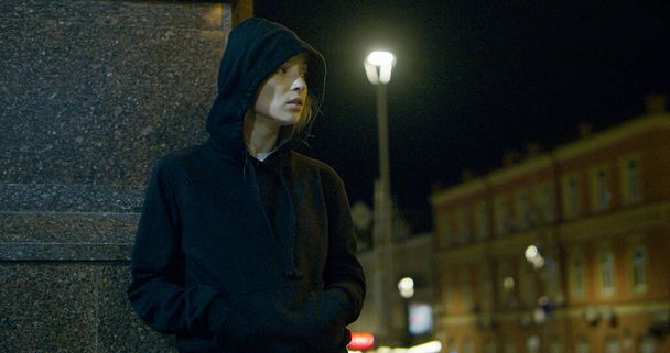 Mulher misteriosa de pé luzes da cidade vestindo capuz na rua da noite.  - Foto, Imagem