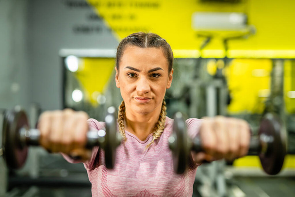 Retrato de una mujer caucásica adulta entrenando en el gimnasio levantando pesas pesas entrenamiento de hombros atleta mujer personas reales concepto de salud y fitness - Foto, Imagen