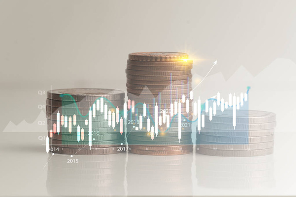 Stack di monete isolate da sfondo bianco con linee grafiche che riportano la crescita degli utili societari derivata dalla valutazione degli investimenti economici. - Foto, immagini